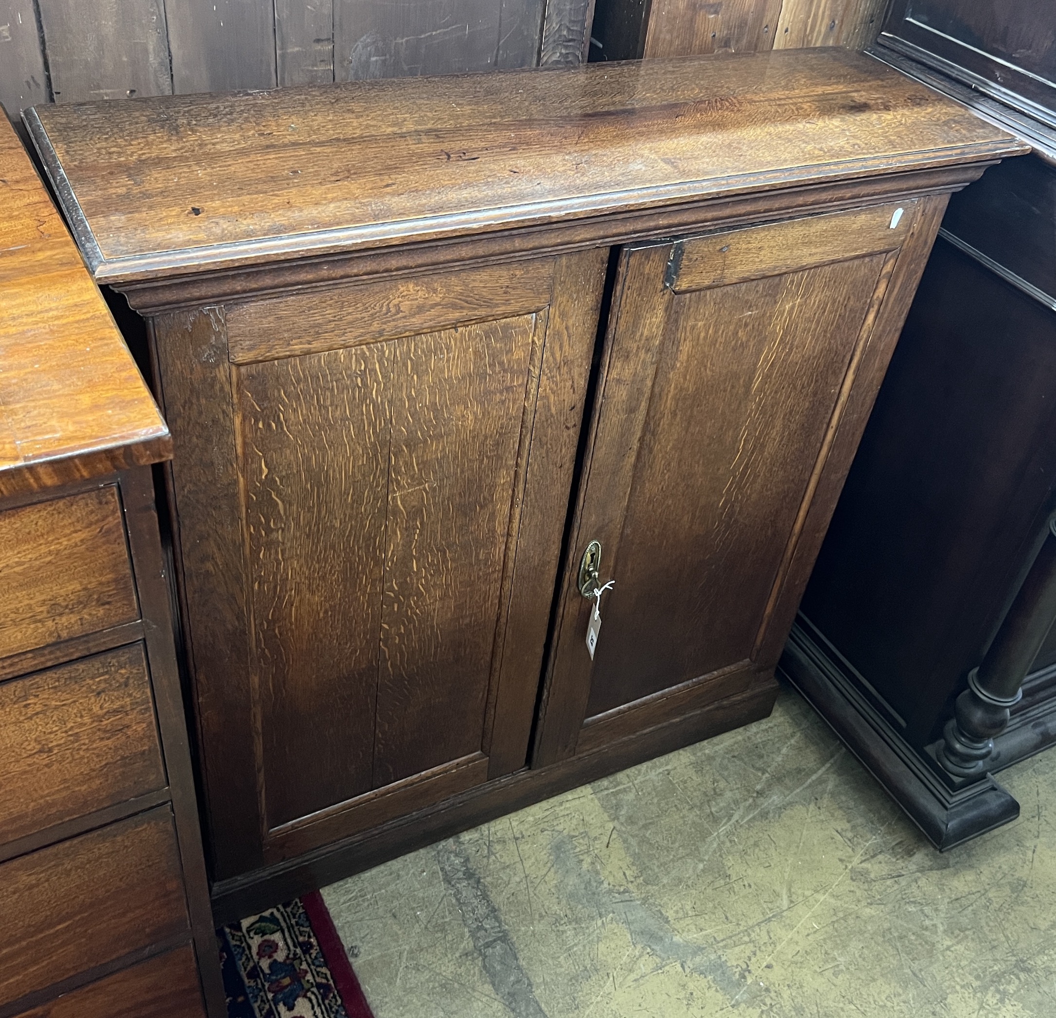 A George III oak two door side cabinet, (adapted) width 100cm, depth 32cm, height 102cm